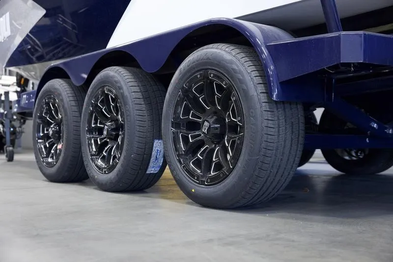 Slide: The Image of Trailer wheels of a 2025 Malibu 24 MXZ boat, featuring sleek black rims. - 7