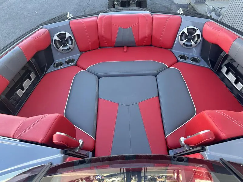 Slide: The Image of 2024 Malibu 23 MXZ boat interior with red and gray seating and built-in speakers. - 14