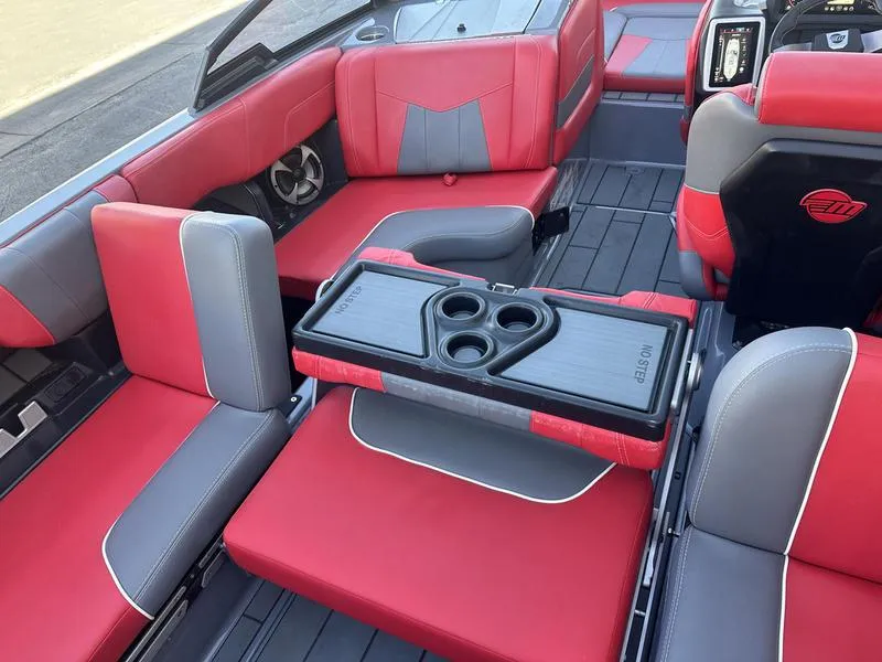 Slide: The Image of 2024 Malibu 23 MXZ boat interior with red and gray seating and cup holders. - 15