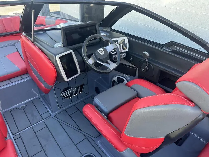 Slide: The Image of 2024 Malibu 23 MXZ boat interior with red and gray seating, modern dashboard, and steering wheel. - 20