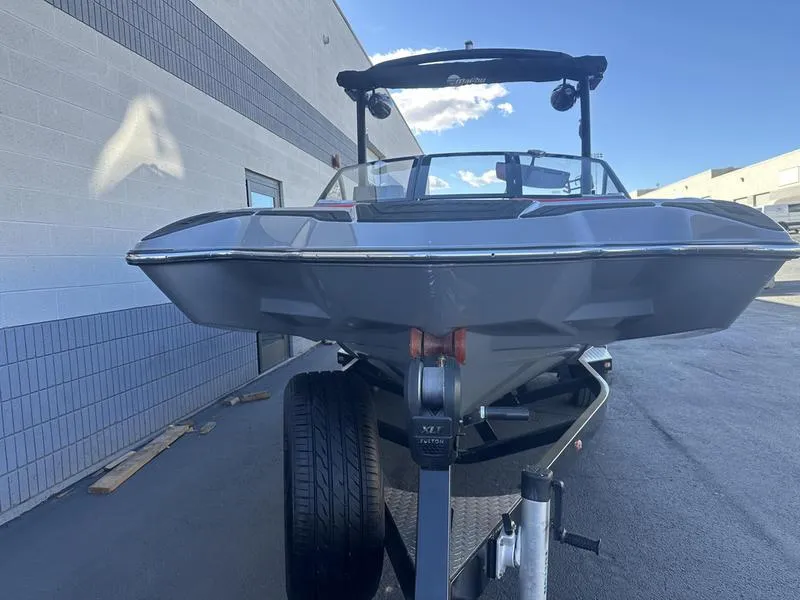 Slide: The Image of 2024 Malibu 23 MXZ boat on trailer, parked outside a building. - 5