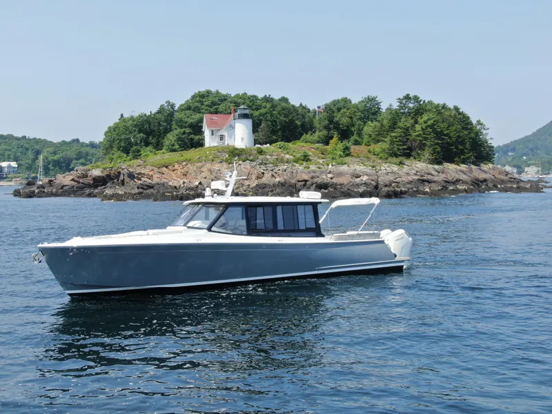 The Image of 2023 MJM 4 boat cruising near a rocky island with a lighthouse. - 0