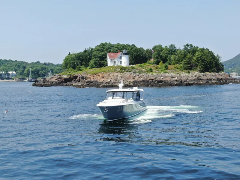 Slide: The Image of 2023 MJM 4 boat cruising near a scenic island with a lighthouse. - 18