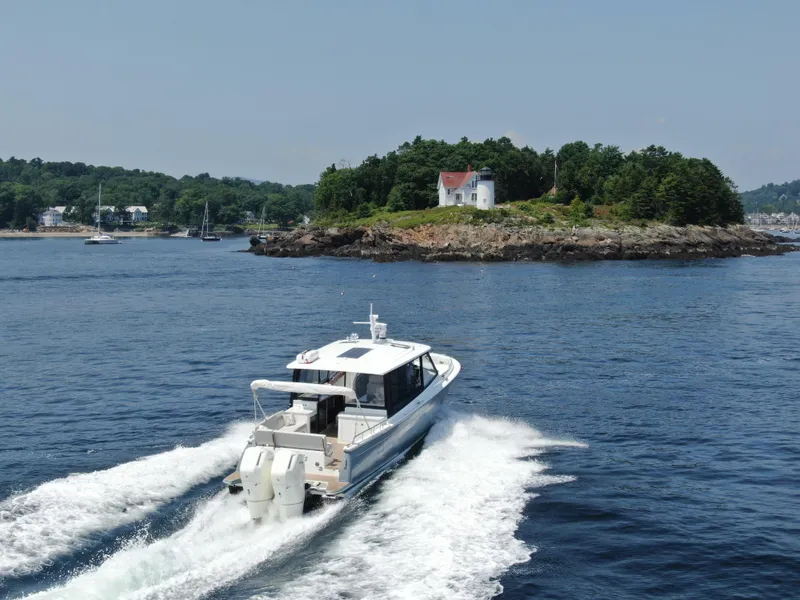 Slide: The Image of 2023 MJM 4 boat cruising near a scenic island with a lighthouse. - 5