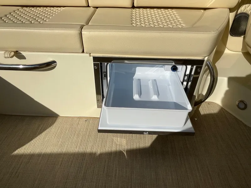 Slide: The Image of 2025 Chris-Craft Launch 28GT interior with open storage compartment and beige seating. - 14