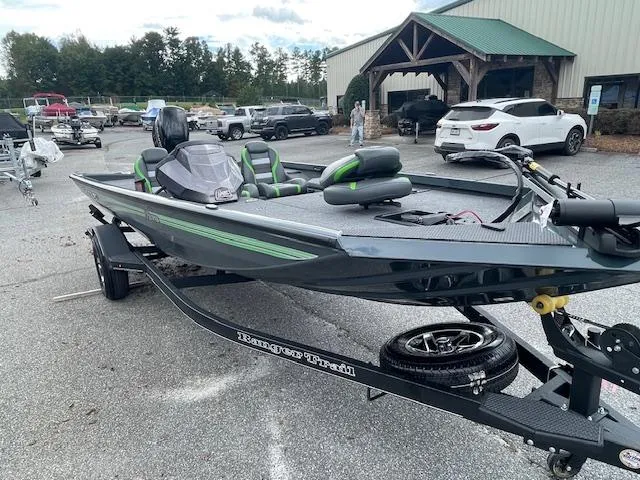 Slide: The Image of 2025 Ranger RT178 boat on trailer, parked outdoors near vehicles and building. - 2