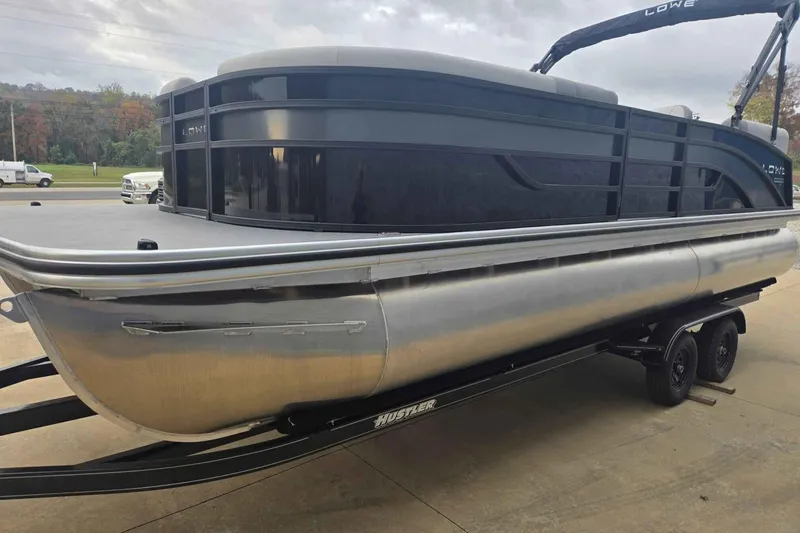 Slide: The Image of 2025 Lowe SS 230 WV pontoon boat on trailer, sleek design, black and silver finish. - 2