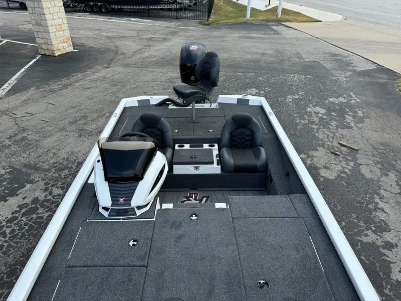 Slide: The Image of 2025 Vexus AVX1980 boat interior with seating and console, parked on pavement. - 27