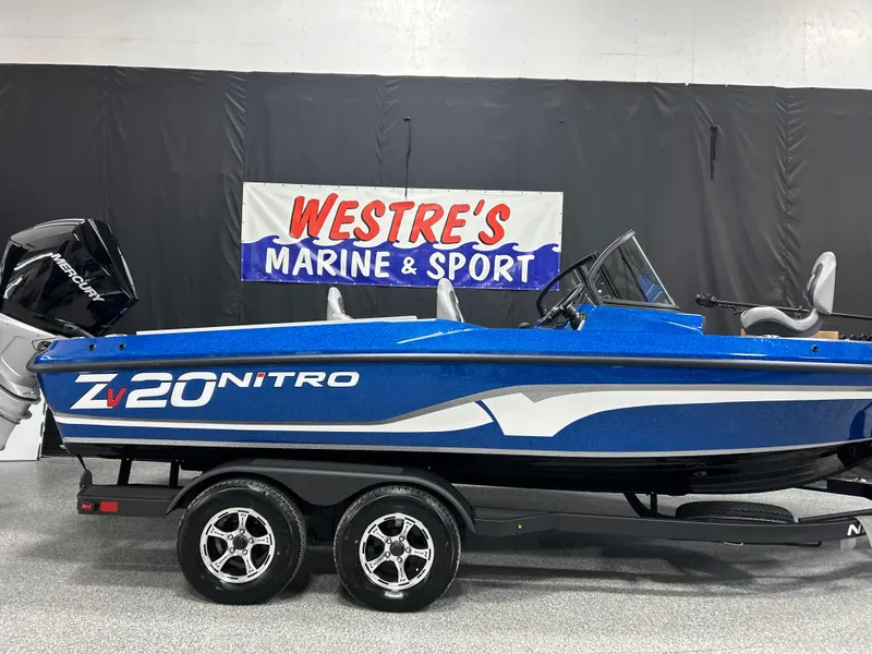 Slide: The Image of 2025 Nitro ZV20 boat in showroom, blue and white design, on trailer at Westre's Marine & Sport. - 1