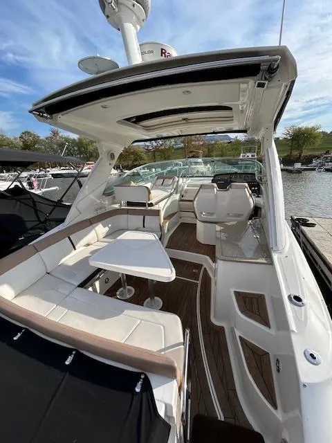 Slide: The Image of 2016 Sea Ray 350 Sundancer boat interior with seating and table, docked by the water. - 4