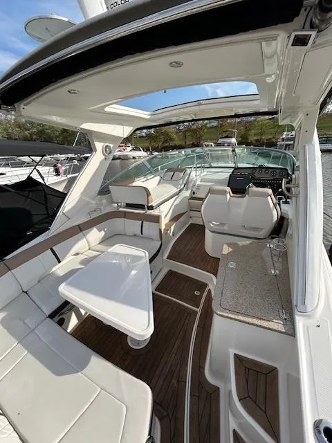 Slide: The Image of 2016 Sea Ray 350 Sundancer interior with seating, table, and helm, docked in marina. - 5