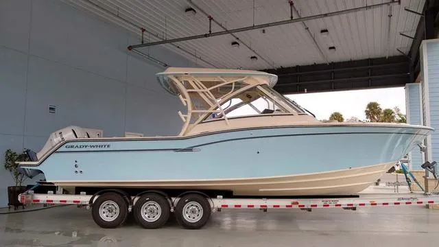 Slide: The Image of 2019 Grady-White Freedom 325 boat on trailer, parked near palm trees and building. - 21