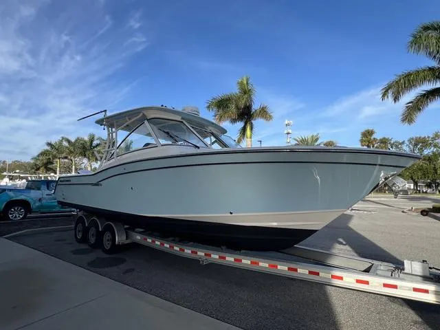 Slide: The Image of 2019 Grady-White Freedom 325 boat on trailer, parked near palm trees. - 4