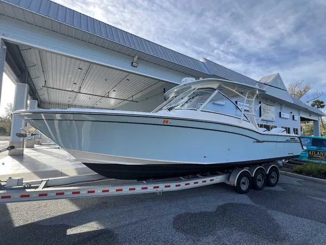 Slide: The Image of 2019 Grady-White Freedom 325 boat on trailer, parked near palm trees and building. - 40