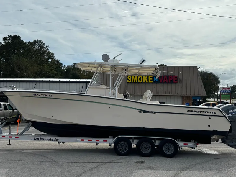 Slide: The Image of 2005 Grady-White Bimini 306 boat on trailer near a vape shop. - 13