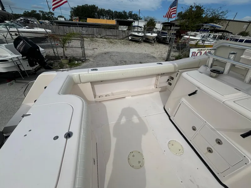 Slide: The Image of 2005 Grady-White Bimini 306 boat interior with seating and storage, docked with American flags. - 22