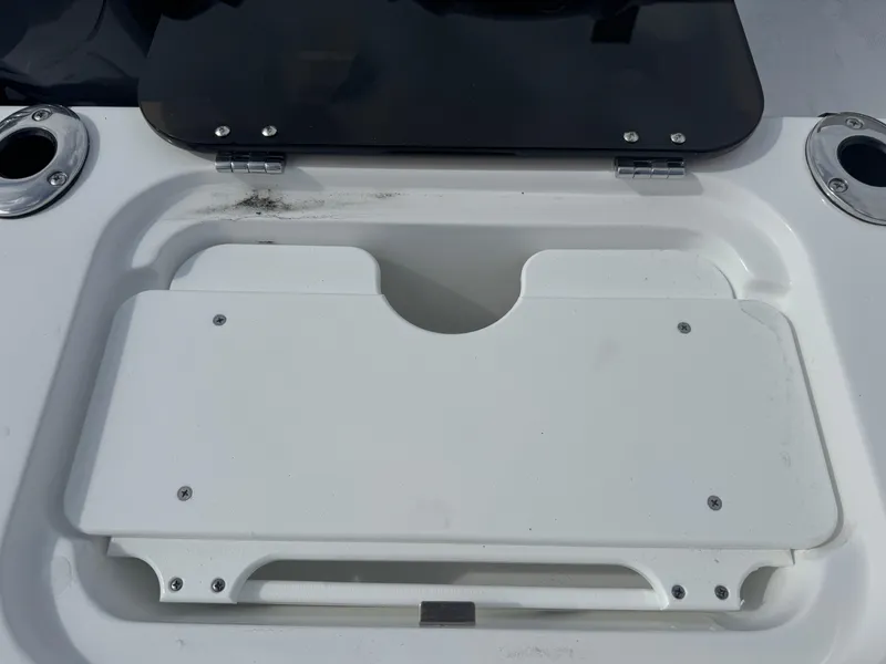 Slide: The Image of Wellcraft 302 Fisherman 2025 boat storage compartment with white lid and cup holders. - 8