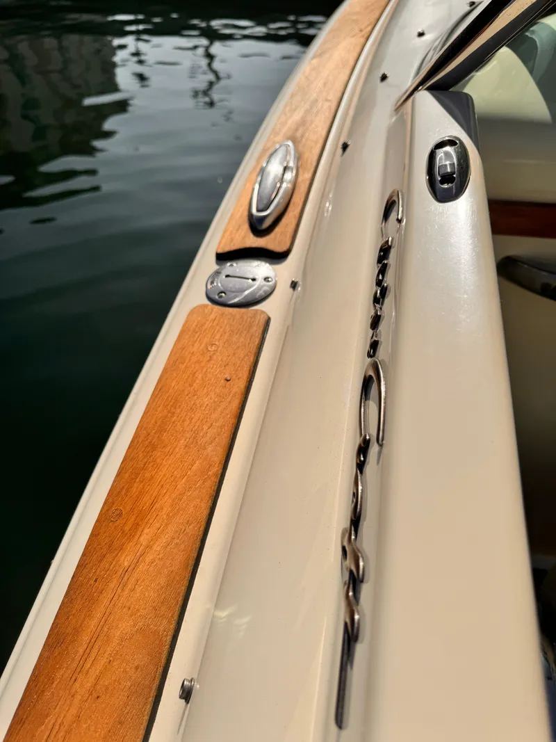 Slide: The Image of 2014 Chris-Craft Launch 25 boat, showcasing sleek design and wood accents by the water. - 10