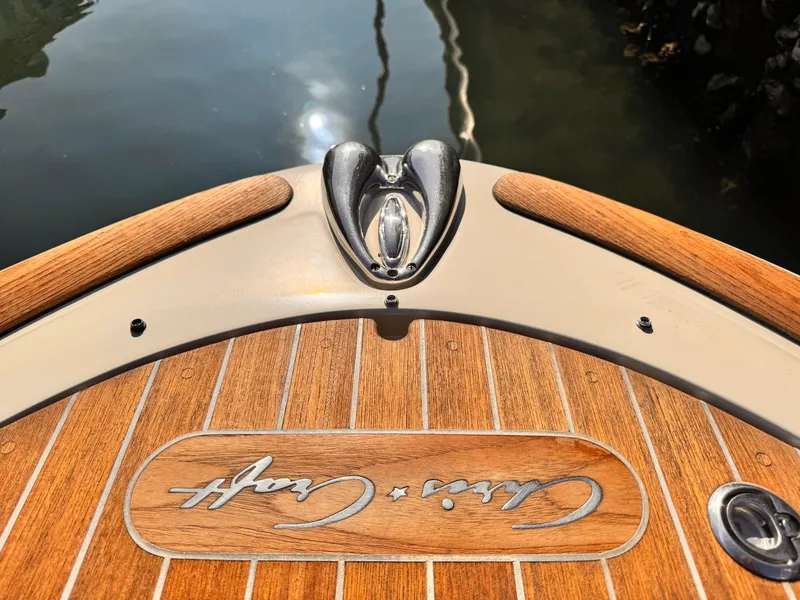 Slide: The Image of 2014 Chris-Craft Launch 25 boat with teak deck and logo, docked on calm water. - 14