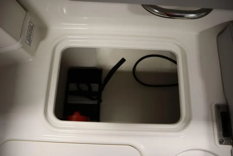 Slide: The Image of 2024 Bayliner 2050 DX boat storage compartment with battery and cables. - 41