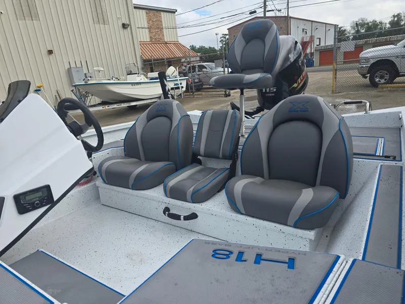 Slide: The Image of 2022 Xpress H18 boat interior with gray and blue seating, steering wheel, and motor. - 10