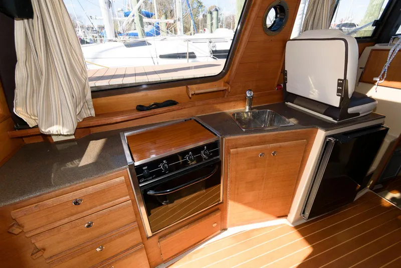 Slide: The Image of Interior of 2015 Ranger Tugs R-29S with kitchenette, stove, sink, and wood cabinetry. - 17
