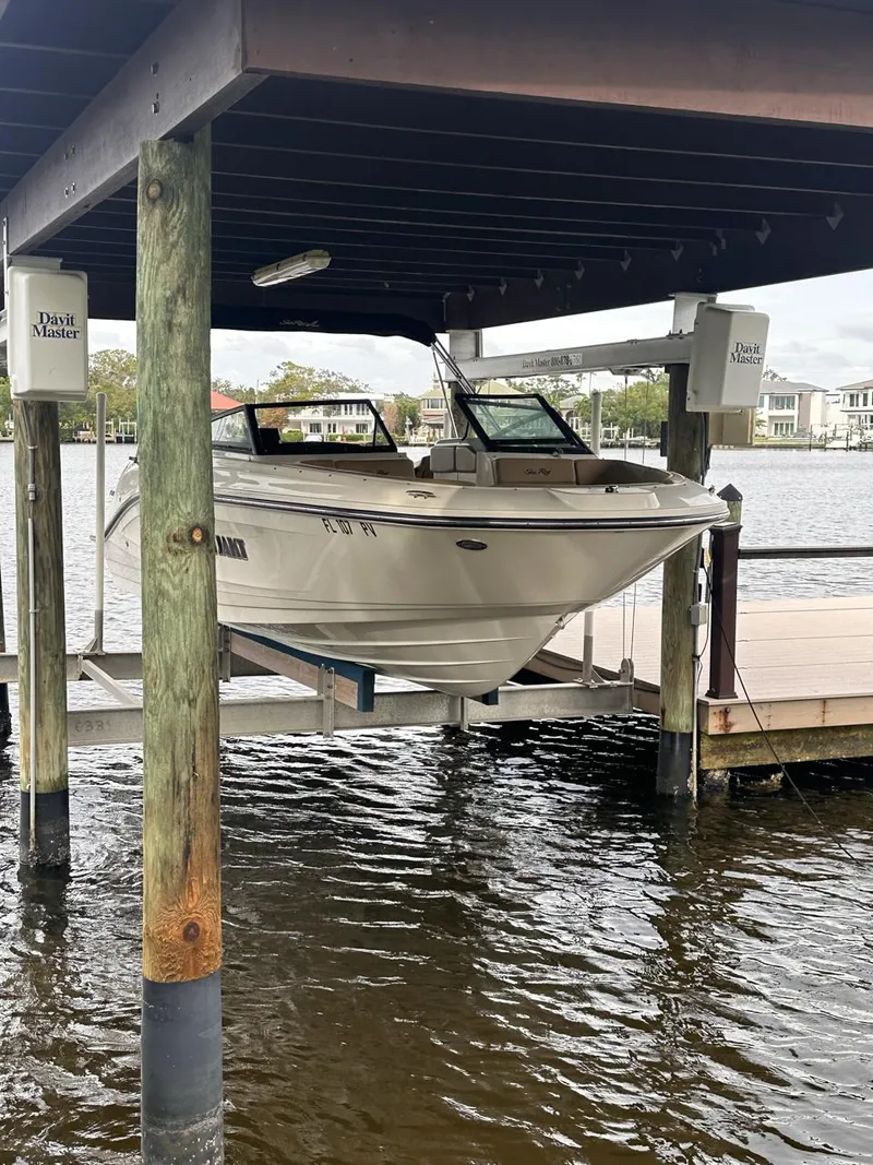 Slide: The Image of 2019 Sea Ray SPX 230 OB boat docked on a lift by the water. - 2