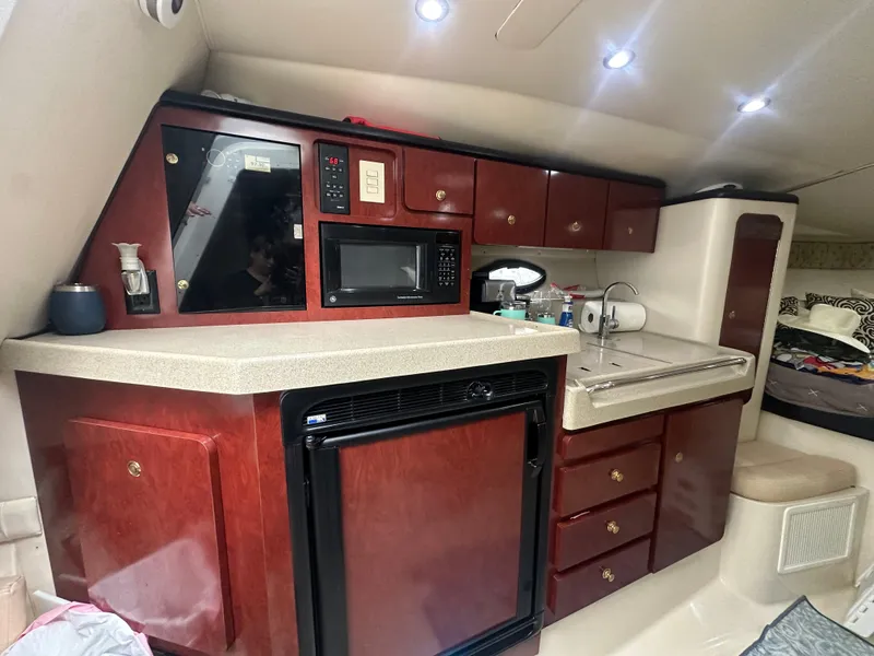 Slide: The Image of 2001 Wellcraft 3300 Martinique cabin kitchen with wood cabinets, microwave, and sink. - 17