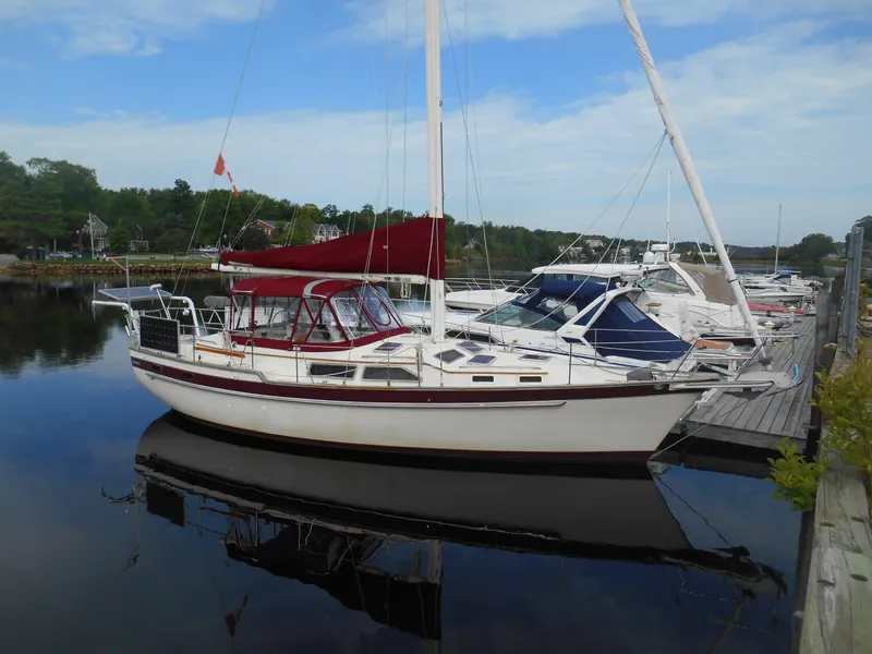 The Image of 1987 Irwin MKII sailboat docked at a marina, featuring a red canopy and calm waters. - 0