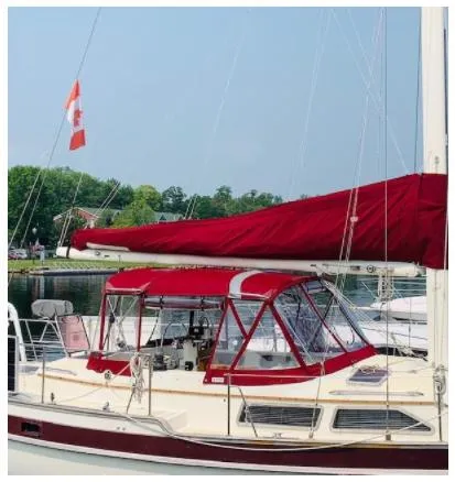 Slide: The Image of 1987 Irwin MKII sailboat with red canopy and Canadian flag, docked in a serene marina. - 1