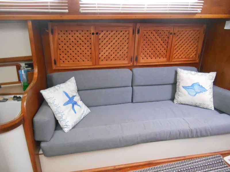 Slide: The Image of 1987 Irwin MKII interior with gray sofa, nautical-themed pillows, and wooden cabinets. - 19