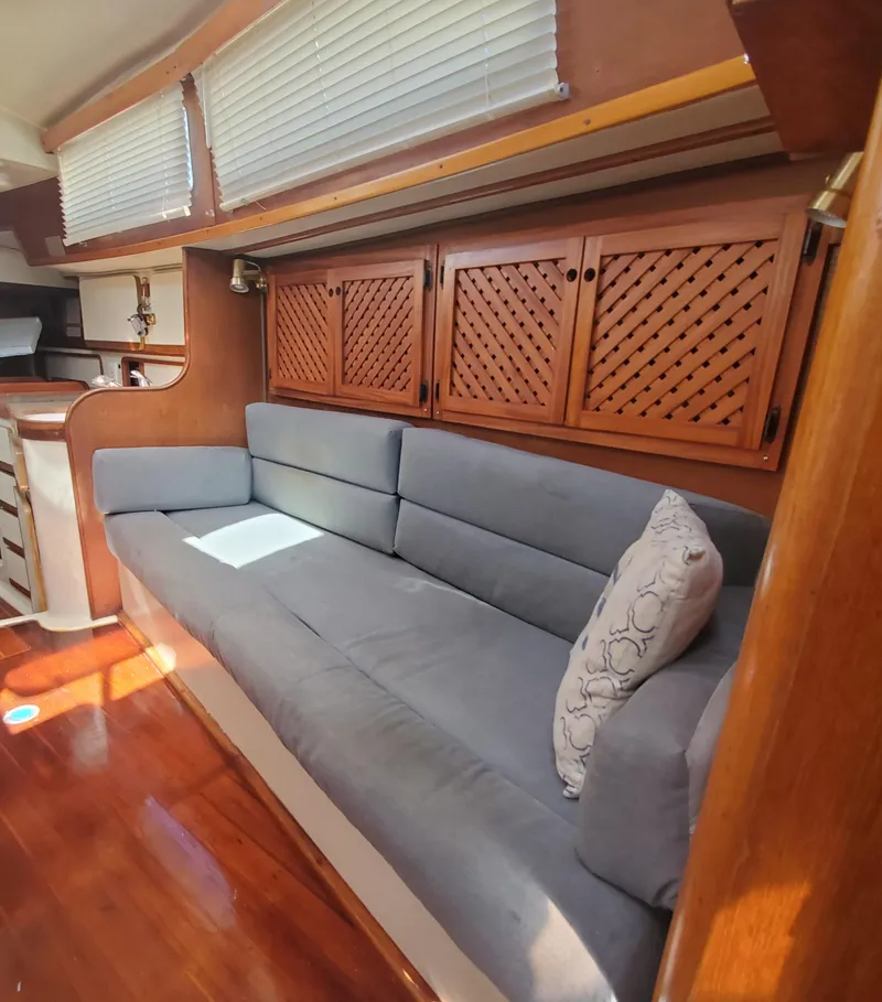 Slide: The Image of 1987 Irwin MKII yacht interior with gray sofa, wooden cabinets, and decorative pillow. - 21