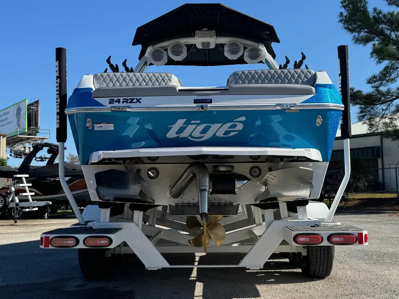 Slide: The Image of 2025 Tigé 24RZX boat, rear view, blue and white design, parked on trailer. - 3