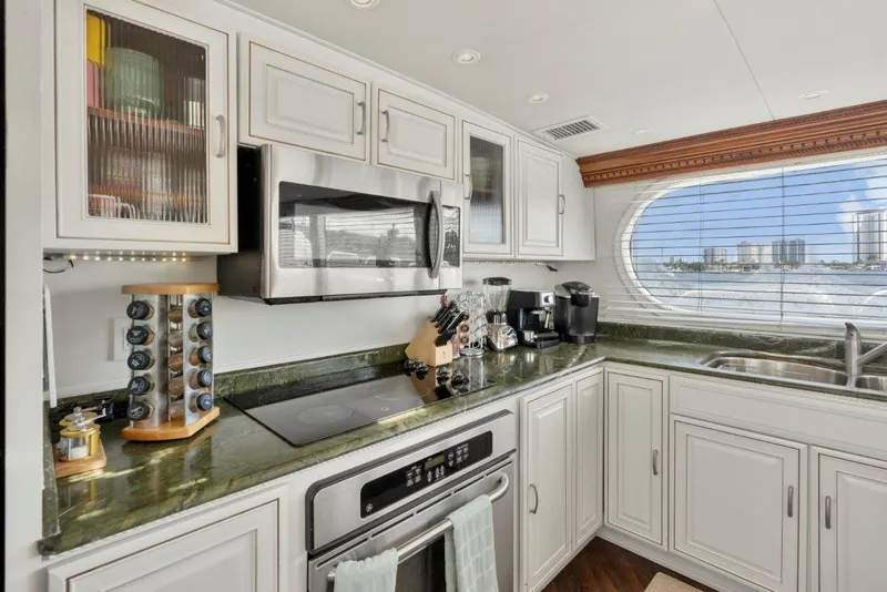 Slide: The Image of Luxurious kitchen interior of 1984 Broward 110 Motor Yacht with modern appliances and scenic window view. - 19
