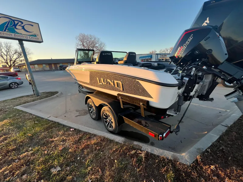Slide: The Image of 2025 Lund 219 Pro-V GL boat on trailer at dealership parking lot. - 1