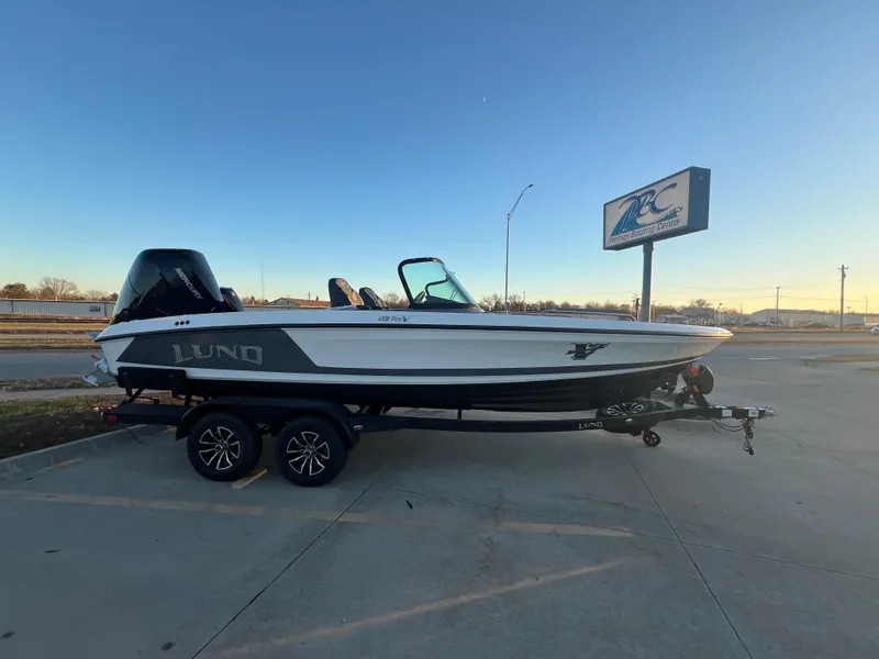 Slide: The Image of 2025 Lund 219 Pro-V GL boat on trailer in parking lot, clear sky background. - 11