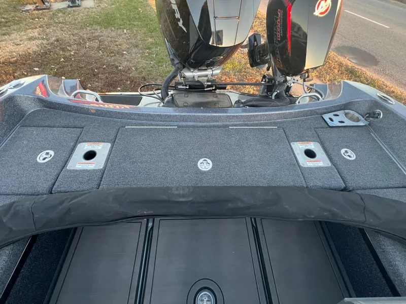 Slide: The Image of 2025 Lund 219 Pro-V GL boat deck with motor, storage compartments, and fishing rod holders. - 6