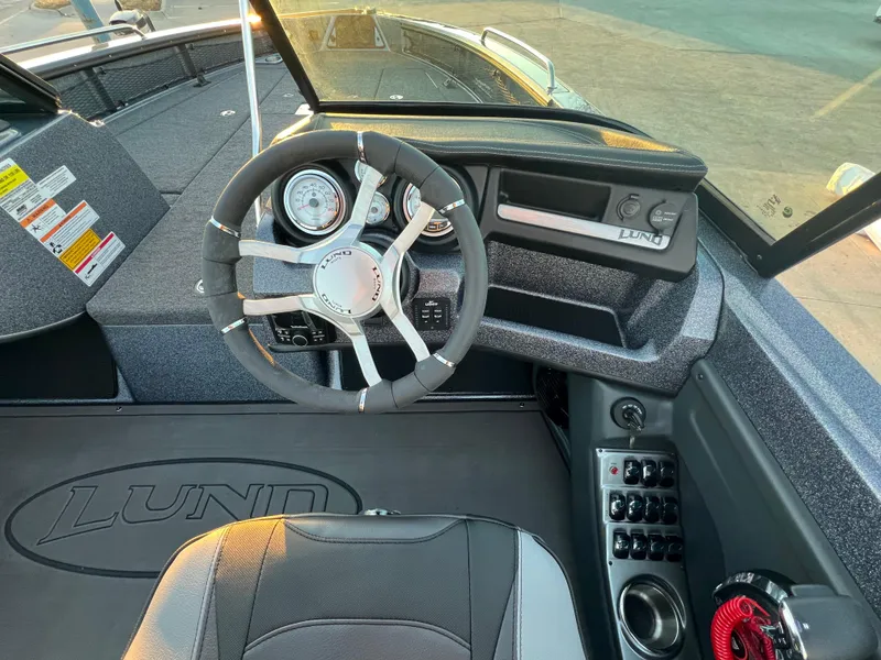 Slide: The Image of 2025 Lund 219 Pro-V GL boat interior with steering wheel and dashboard controls. - 7