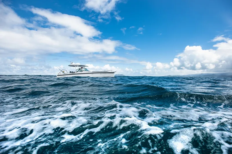 Slide: The Image of Axopar 28 T-Top 2023 boat cruising on open ocean under blue sky. - 7