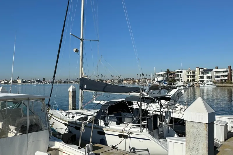Slide: The Image of Sailboat docked at marina, Hunter 35 model, clear blue sky, waterfront homes in background. - 12