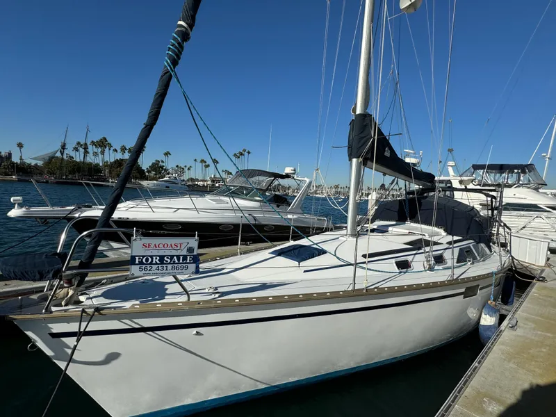 Slide: The Image of 1992 Hunter 35 sailboat docked, for sale sign visible, clear blue sky background. - 2
