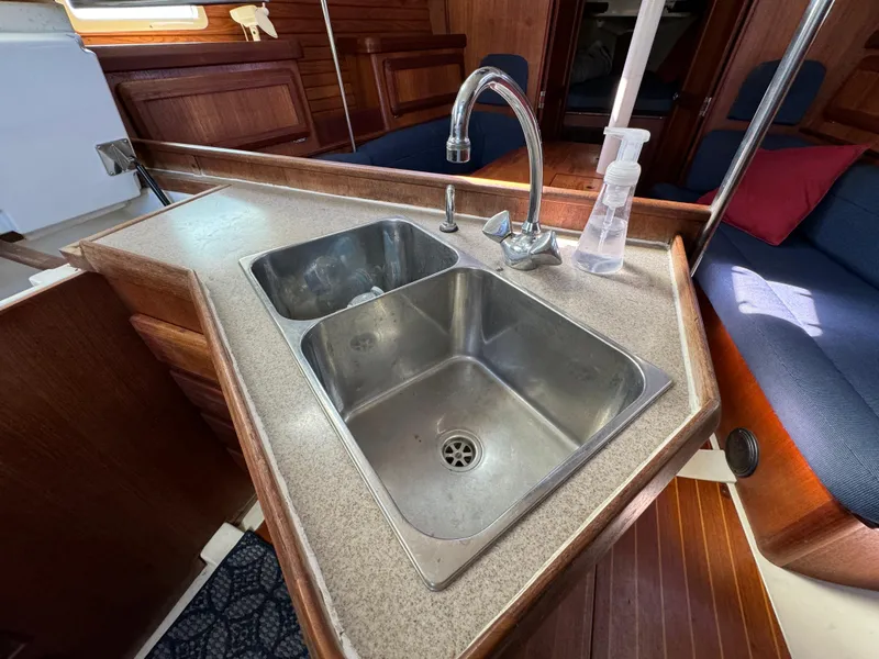 Slide: The Image of 1992 Hunter 35 yacht kitchen sink with faucet, wooden interior, and seating area. - 41