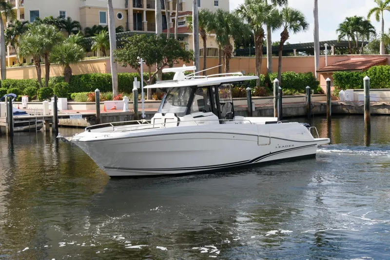 The Image of 2023 Jeanneau Leader 10.5 CC boat docked in a marina with palm trees. - 0