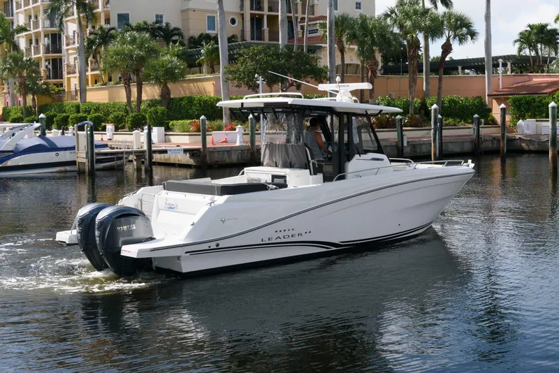 Slide: The Image of 2023 Jeanneau Leader 10.5 CC boat docked in a marina with palm trees. - 2