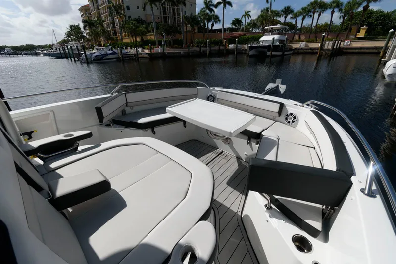 Slide: The Image of 2023 Jeanneau Leader 10.5 CC boat interior with seating and table, docked by waterfront. - 21