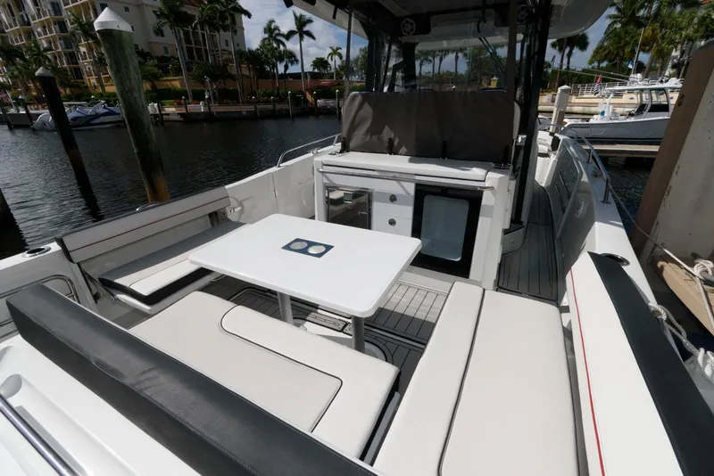 Slide: The Image of 2023 Jeanneau Leader 10.5 CC boat interior with seating and table in marina setting. - 5