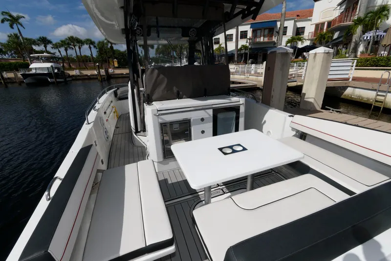 Slide: The Image of 2023 Jeanneau Leader 10.5 CC boat interior with seating and table at marina. - 6