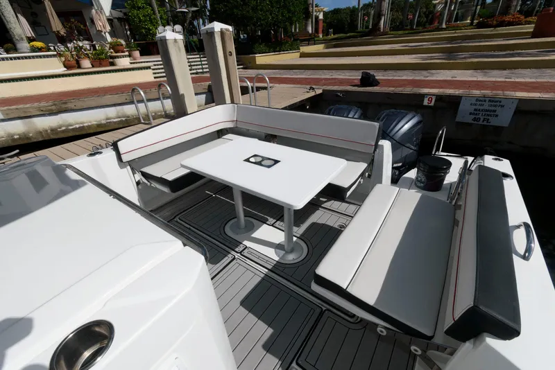 Slide: The Image of 2023 Jeanneau Leader 10.5 CC boat interior with seating and table at dock. - 7