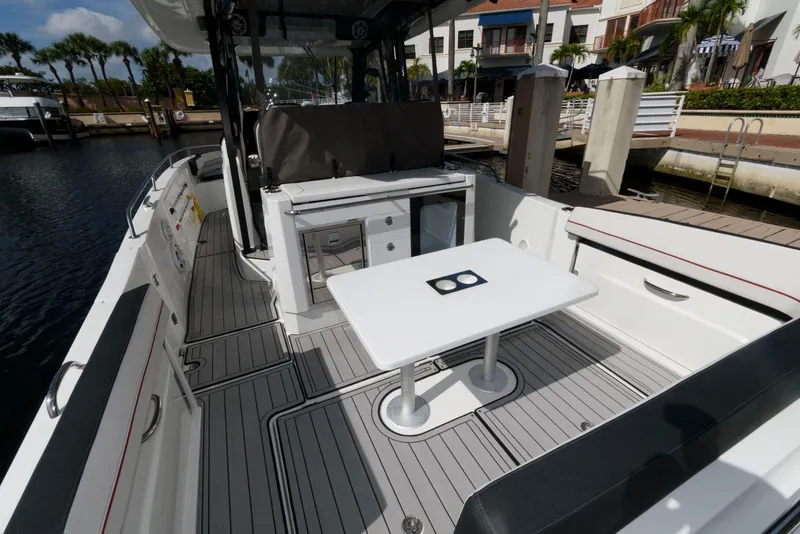 Slide: The Image of 2023 Jeanneau Leader 10.5 CC boat interior with seating and table in a marina setting. - 8