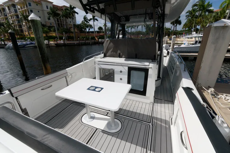 Slide: The Image of 2023 Jeanneau Leader 10.5 CC boat interior with table and seating, docked at marina. - 9